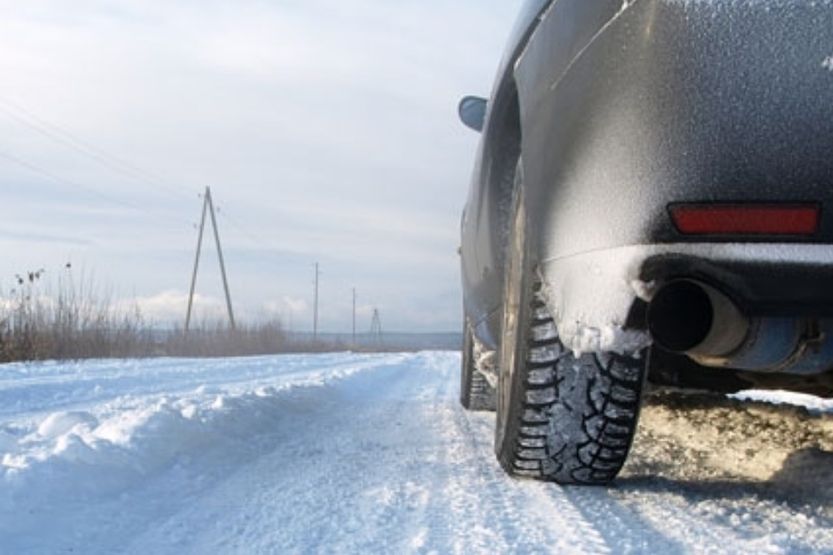 Henkilöauto ajaa lumisella tiellä